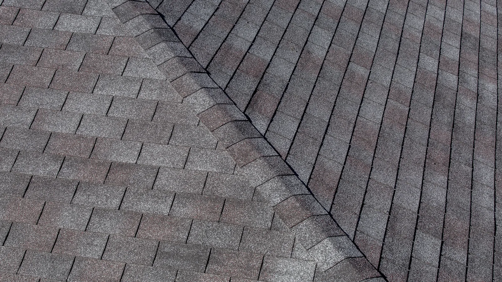 Hip ridge line crossing gray three-tab asphalt shingle slopes